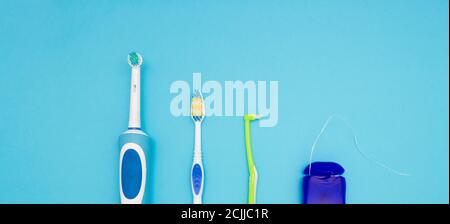 Mundhygiene. Teil einer elektrischen Zahnbürste, Zahnbürsten und Zahnseide auf blauem Hintergrund. Der Blick von oben. Stockfoto