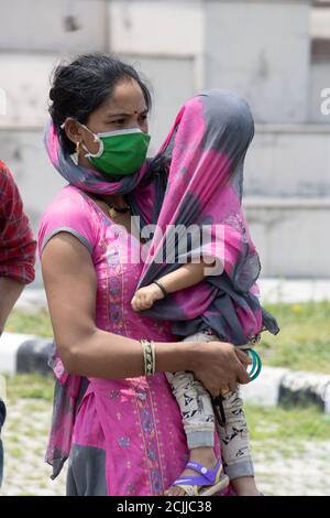Dehradun, Uttarakhand/Indien - September 08 2020: Eine Mutter, die mit ihrem Kind Masken trägt, bedeckt ihr Kind mit einem Tuch. Stockfoto