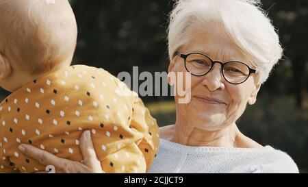 Glückliche Großmutter hält ihr Enkelkind in der Natur. Hochwertige Fotos Stockfoto
