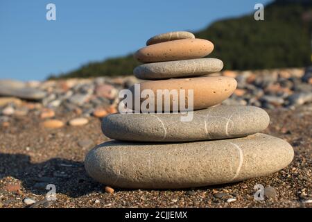 Handgefertigter Turm aus Steinen auf einem Kies- und Sandstrand. Pyramide aus grauen Kieselsteinen. Zen-Skulptur. Tapete. Sommerurlaub Konzept. Stockfoto