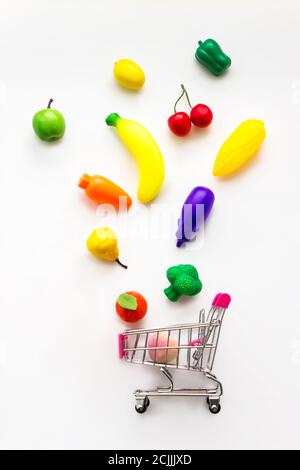 Mini Spielzeug Gemüse und Obst fallen in Mini-Warenkorb auf weißem Hintergrund. Konzept für gesundes frisches Gemüse. Kreative Idee Stockfoto