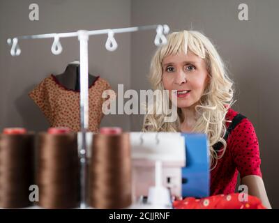 Horizontales Porträt einer lächelnden kaukasischen Frau Schneiderin nähen Stoff In ihrer Werkstatt Stockfoto