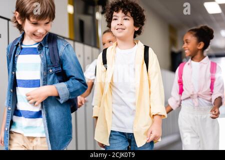 Aufgeregt multikulturelle Schüler zu Fuß entlang Schulkorridor Stockfoto