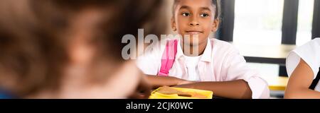 Horizontale Ernte der afroamerikanischen Schulmädchen sitzt in der Schule essen Zimmer in der Nähe der Lunchbox Stockfoto