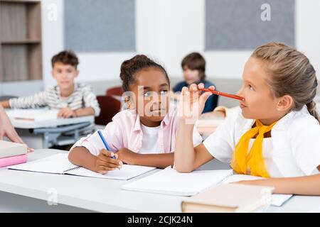 Selektiver Fokus der multiethnischen Schülerinnen schreiben auf Notebooks während des Unterrichts Im Klassenzimmer Stockfoto