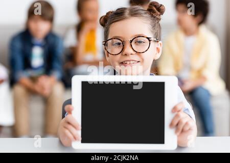 Selektive Fokus der Schülerin in Brillen halten digitale Tablette an Schreibtisch Stockfoto