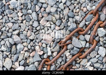 Verrostete Kette auf Kies. Abstrakte Hintergrundtextur. Stockfoto