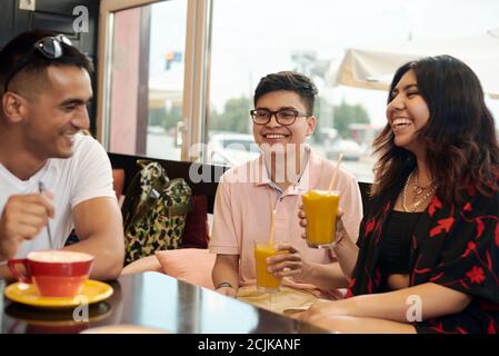 Treffen von Freunden. Drei multiethnische Freunde diskutieren etwas und lachen darüber. Stockfoto