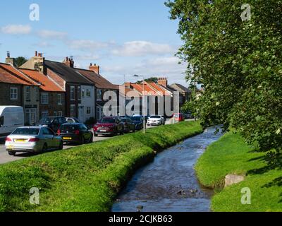 Hauptstraße von Swainby Village North Riding von Yorkshire England Großbritannien mit Scugdale Beck Bach durch das Dorfzentrum Stockfoto