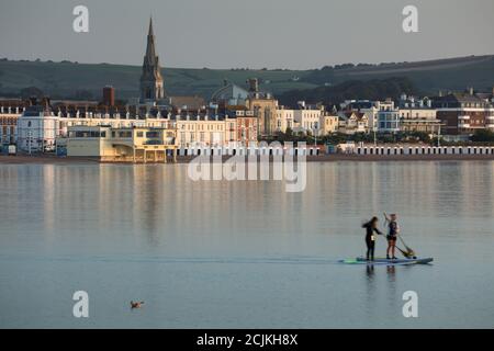 Zwei Paddle-Boarder in Weymouth Bay at Dawn, Jurassic Coast, Dorset, England, Großbritannien Stockfoto