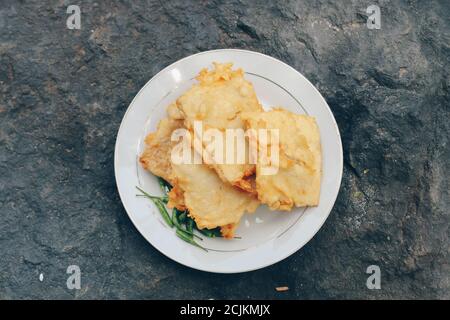 Tempe Mendoan ist eine Art von Tempeh Gericht aus dünnen Tempeh, und in Mehl gebraten, so dass es schmeckt lecker und knusprig mit Soja-Sauce in Holzplatte ist Stockfoto