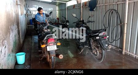 DISTRIKT KATNI, INDIEN - 15. SEPTEMBER 2019: Ein asiatisches Motorrad-Service-Personal, das Fahrräder mit Wasserdruck auf indische Autowerkstatt wascht. Stockfoto