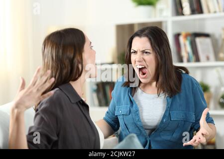 Zwei Mitbewohner streiten und schreien auf einer Couch im Wohnzimmer zu Hause Stockfoto