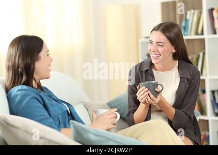 Zwei glückliche Freunde im Gespräch sitzen auf einer Couch im Wohnzimmer zu Hause Stockfoto