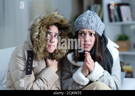 Zwei Mitbewohner zittern an einem kalten Wintertag an einem Couch im Wohnzimmer zu Hause Stockfoto