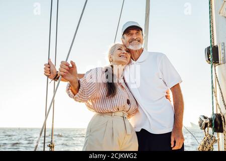 Glücklich reifes Paar umarmt einander und wegschauen. Zwei Menschen stehen auf einem Segelboot und lächeln. Stockfoto