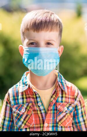 Porträt eines kleinen Jungen in einer Schutzmaske auf der Straße während der Coronavirus und Covid-Pandemie - 19 Stockfoto