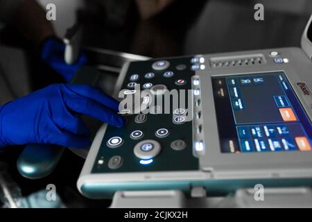 Ein Tierarzt tut ein Ultraschall der Auge des Hundes im Büro. Der männliche Arzt hand auf ein Ultraschallgerät. Tierklinik Hintergrund. Stockfoto