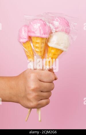 Verschiedene Lutscher in der Hand eines Kindes auf einem rosa Hintergrund Stockfoto