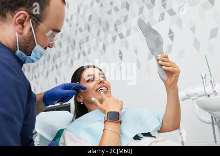 Menschen, Medizin, Stomatologie und Gesundheitsversorgung Konzept - glücklich männlichen Zahnarzt zeigt Arbeitsplan für Frau Patienten in der Zahnklinik Büro Stockfoto