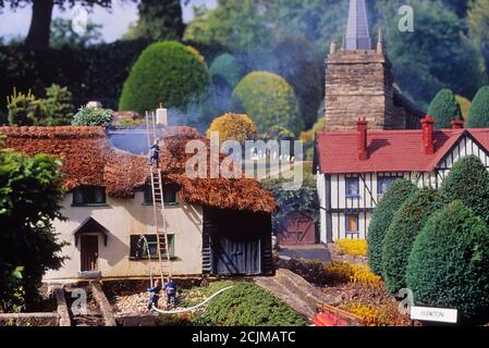 Modellfeuermänner Besuchen Sie ein Feuer in einem Reethaus in Hanton Weiler, Bekonscot Modelldorf und Eisenbahn, Bekonscot Modelldorf. Beaconsfield. Buckinghamshire, Chilterns, England, Großbritannien Stockfoto