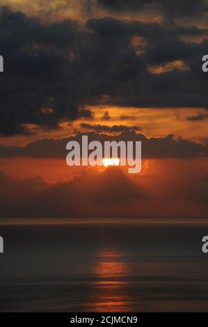 Spektakulärer Sonnenuntergang über dem Atlantischen Ozean mit dünnen Wolken wie geschmolzene Lava, monochromatischen Vien mit dunkelgrauen und goldgelben Tönen des Sonnenlichts Stockfoto