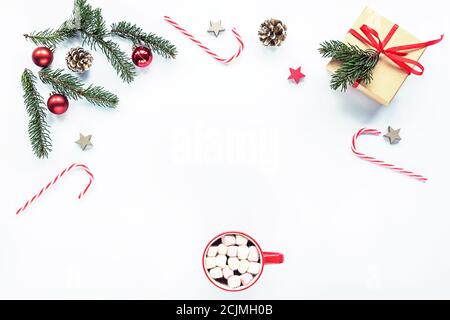 Weihnachtsrahmen aus Tannenzweigen, roten Süßigkeiten, Zapfen, Tasse Kakao mit Marsmalows, Dekorationen. Weihnachten oder Neujahr Hintergrund. Flach legen, oben vi Stockfoto