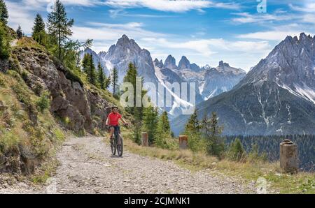 Nette und aktive ältere Frau, die ihr elektrisches Mountainbike reitet Auf einer alten Militärstraße von Toblach bis zum Gipfel der Marchkinkele eith spektakulär Stockfoto