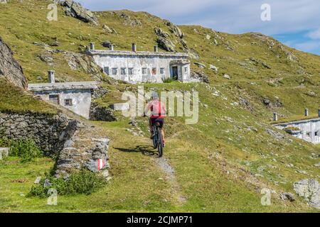 Nette und aktive ältere Frau, die ihr elektrisches Mountainbike reitet Auf einer alten Militärstraße von Toblach bis zum Gipfel der Marchkinkele eith spektakulär Stockfoto