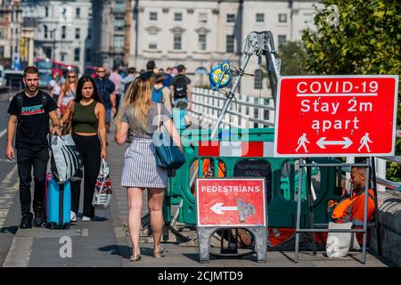 London, Großbritannien. September 2020. Die Leute achten nicht zu sehr auf ein 2m-auseinander-Schild, wenn sie über die Waterloo-Brücke gehen - Einschränkungen für Coronavirus (covid19) beginnen wieder zu bauen Kredit: Guy Bell/Alamy Live News Stockfoto