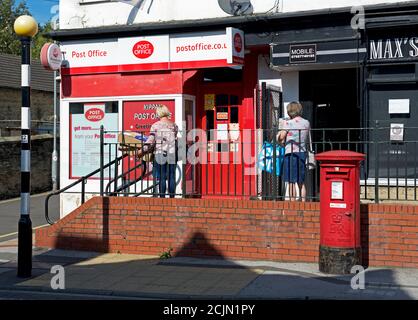Zwei Frauen stehen vor dem Postamt in Kippax, West Yorkshire, England Stockfoto