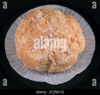Kleines Brötchen mit Creme auf dunklem Hintergrund. Draufsicht Stockfoto