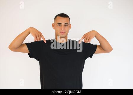 Junger sportlicher Mann vor weißem Hintergrund zeigt mit Fingern nach unten, positives Gefühl Stockfoto