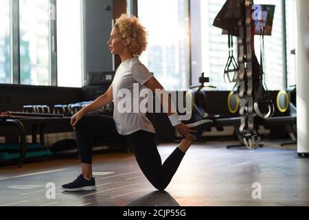 Seitenansicht der jungen Frau, die sich vor dem Sporttraining aufwärmt Im Fitnessstudio Stockfoto