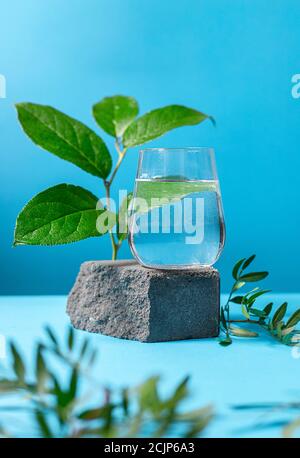 Glas reines Wasser auf Sockel in modischem Stil auf blauem Hintergrund. Stockfoto