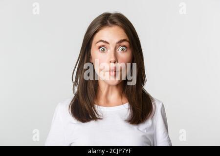 Close-up von lustigen und niedlichen Brünette Mädchen suckink Lippen, so dass Fisch Grimasse, weißer Hintergrund Stockfoto