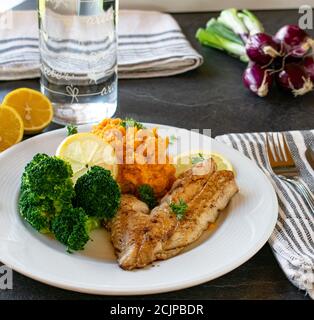 Fisch mit Süßkartoffeln und Brokkoli auf dem Tisch serviert - bereit zu essen Stockfoto