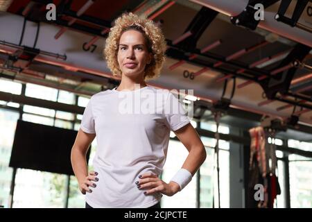 Portrait von jungen gesunden weiblichen Instruktor Blick auf die Kamera während Stehen im Health Club Stockfoto