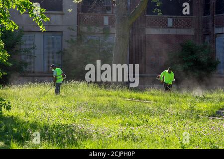 Detroit, Michigan - Arbeiter der Detroit Grounds Crew schneiden das Gras auf dem Gelände der Burbank School, einer von Dutzenden von geschlossenen öffentlichen Schulen i Stockfoto