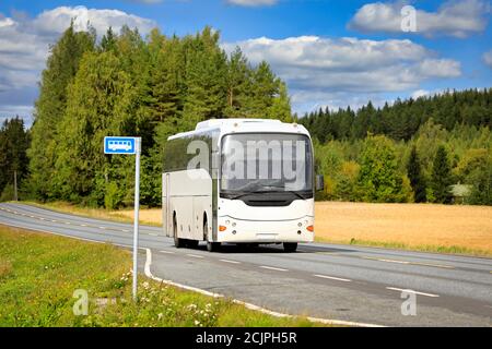 Weißer Reisebus fährt auf der Autobahn durch die Landschaft an einem schönen Sommertag. Stockfoto