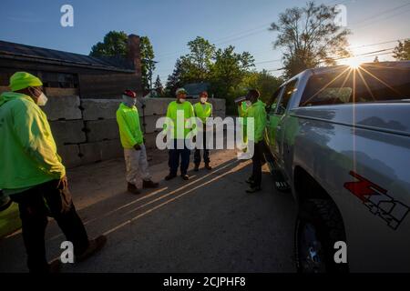 Detroit, Michigan - Arbeiter der Detroit Grounds Crew treffen sich im Morgengrauen, bevor sie auf dem Gelände geschlossener öffentlicher Schulen das Gras schneiden. Stockfoto