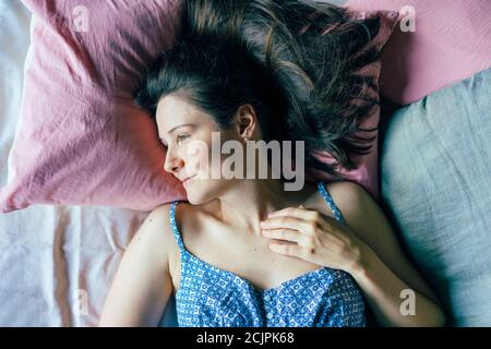 Junge Frau nach dem Aufwachen am Morgen liegt auf dem Bett. Stockfoto