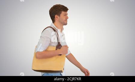 Schöner lächelnder Mann im weißen Hemd, der mit einer Tasche geht Auf seinem Sh Stockfoto