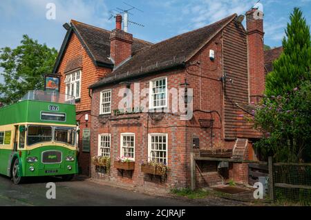 Das Sloop Inn Pub mit einem alten grünen Doppeldeckerbus, der vor dem Hotel in der Nähe von Scaynes Hill, West Sussex, Großbritannien, geparkt ist Stockfoto