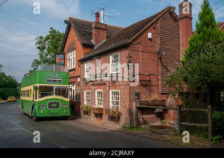 Das Sloop Inn Pub mit einem alten grünen Doppeldeckerbus, der vor dem Hotel in der Nähe von Scaynes Hill, West Sussex, Großbritannien, geparkt ist Stockfoto