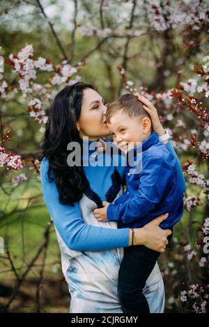 Glückliche Mutter und Sohn während des Spaziergangs im blühenden Frühlingsgarten. Stockfoto