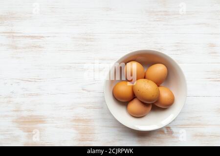 Draufsicht auf frei-Bereich Bio-Eier in Schüssel. Teller mit braunen Hühnereiern auf Holztisch flach legen. Braune Eier in Schüssel auf Holz Hintergrund kopieren Raum Stockfoto