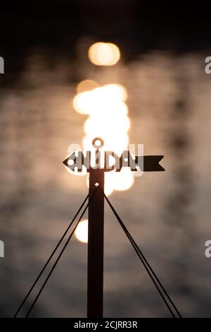 Nida, Litauen, Logo mit Reflexionen der Sonne auf dem Wasser auf dem Hintergrund, vertikal Stockfoto