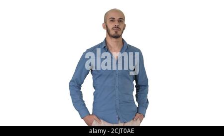 Schöner junger arabischer Mann trägt ein lässiges Outfit zu Fuß, indem seine beiden Hände in seine Taschen auf weißem Hintergrund. Stockfoto
