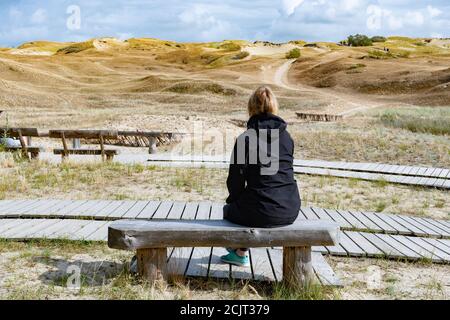 Blonde weibliche Haare auf der Holzbank Blick auf Nagliai Naturschutzgebiet in Neringa, Litauen. Abgestorbene Dünen, Sandhügel von starken Winden gebaut, mit rav Stockfoto